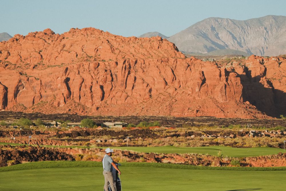 A golf course laid out below red rock cliffs in Southern Utah