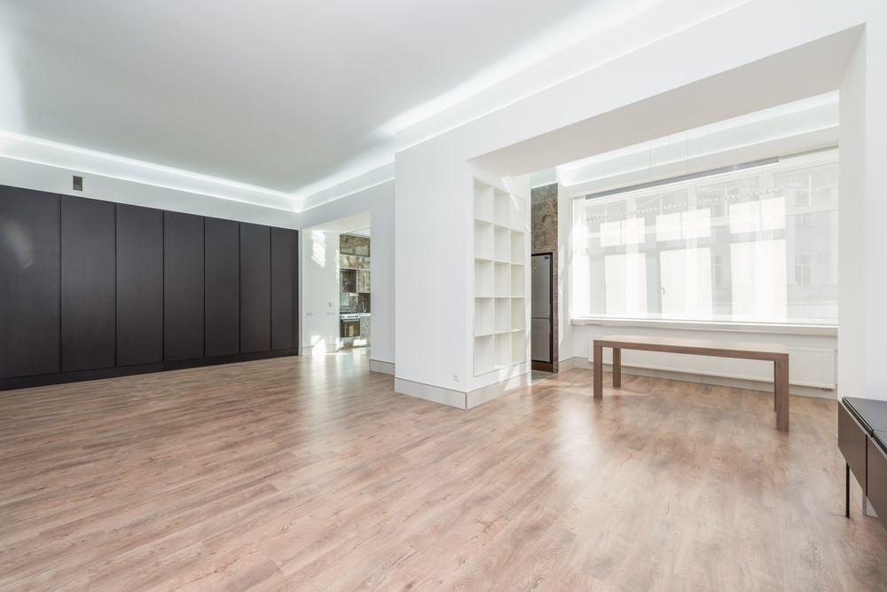 A sunlit room with hardwood floors and tall windows